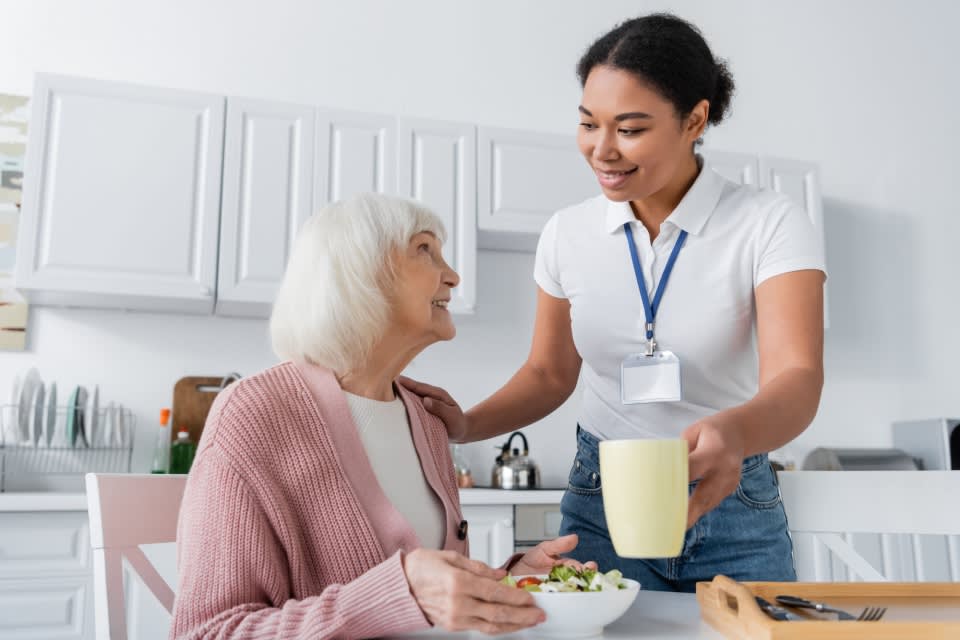 Caregiver helping elderly woman in the kitchen