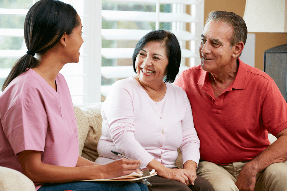 Middle aged couple talking with younger woman who is writing on a clipboard.