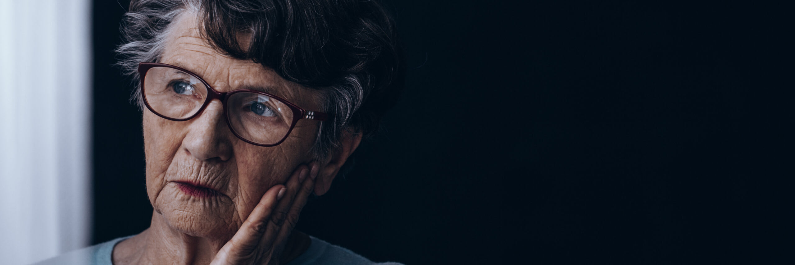 A senior woman rest her hand on her face.